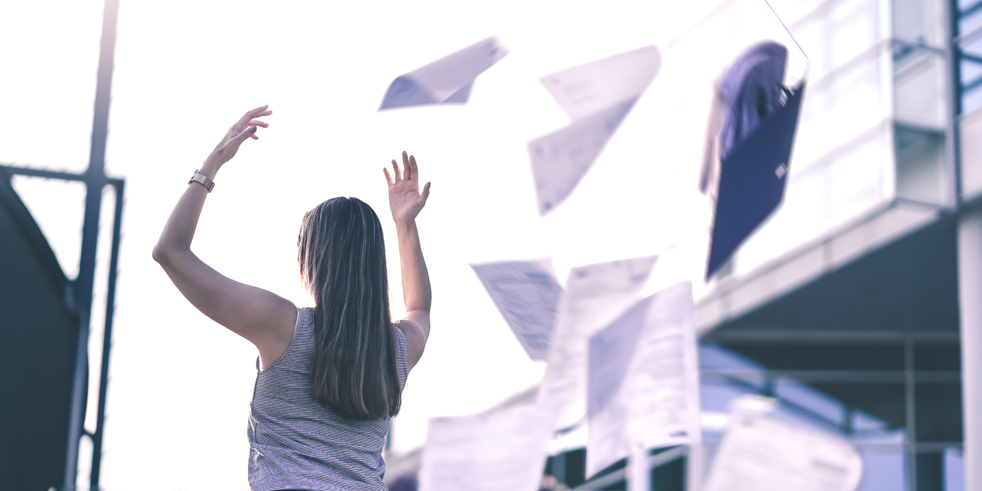 Woman throwing work papers in air in frustration